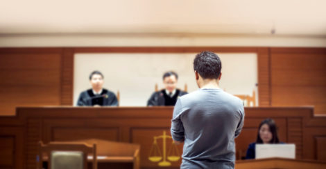 Man in court standing before two judges